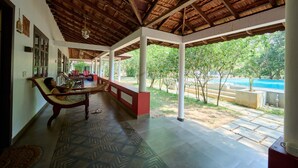 Un espacio al aire libre cubierto con un banco, un suelo estampado y vista a una piscina.