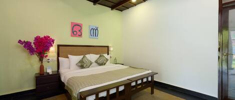 A bedroom with a bed, nightstand, and a vase of flowers.