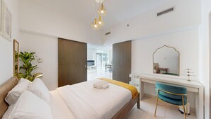 A modern hotel room with a bed, a desk, a mirror, and a potted plant. - 1 Bed Downtown| Walk to Dubai Mall & Burj Khalifa (Downtown Dubai)