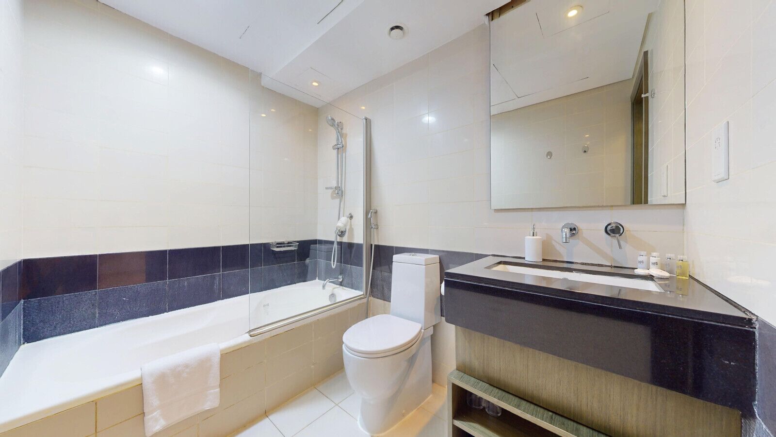 A modern bathroom with a bathtub, toilet, and vanity with a mirror.