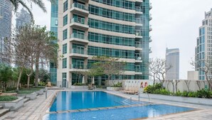 A swimming pool area with a modern building in the background. - 1 Bed Downtown| Walk to Dubai Mall & Burj Khalifa (Downtown Dubai)