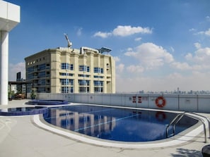 Uma piscina no terraço com vista para a paisagem urbana, um edifício com uma grua e um flutuador na grade.
