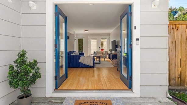 A modern home entrance with a wooden floor, a blue door, and a welcome mat.