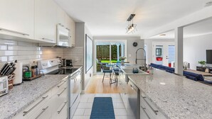 A modern kitchen with white cabinets, granite countertops, and a central island.