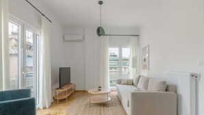 A modern living room with a sofa, a coffee table, and a TV. - Flawless 1BR Apartment in Athens (Menemeni)