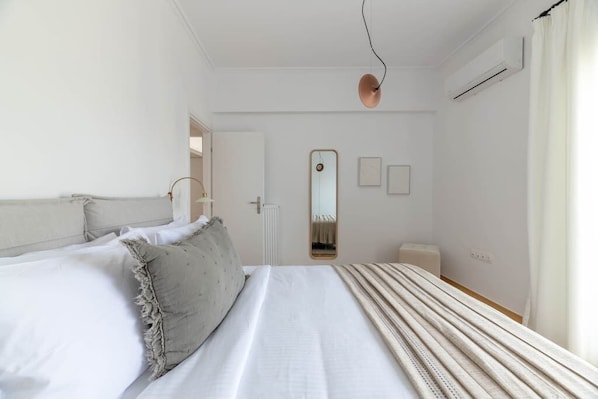A bedroom with a bed, a mirror, and a radiator.