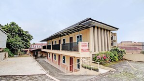 A two-story building with a balcony, a signboard, and a paved courtyard.