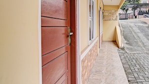 A hallway with a red door, a tiled floor, and a wall-mounted security gate.