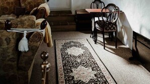 A cozy living room with a sofa, a coffee table, a rug, and a dining area with chairs and a table. - Ashbrook Cottage (Ballymoney)