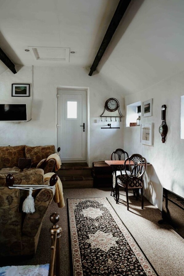 A cozy living room with a sofa, a coffee table, a rug, and a dining area with chairs and a table.