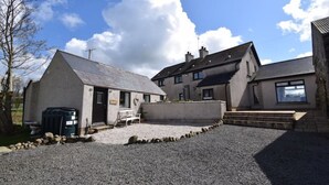 A building with a gravel driveway, a small porch, and a bench. - Ashbrook Cottage (Ballymoney)