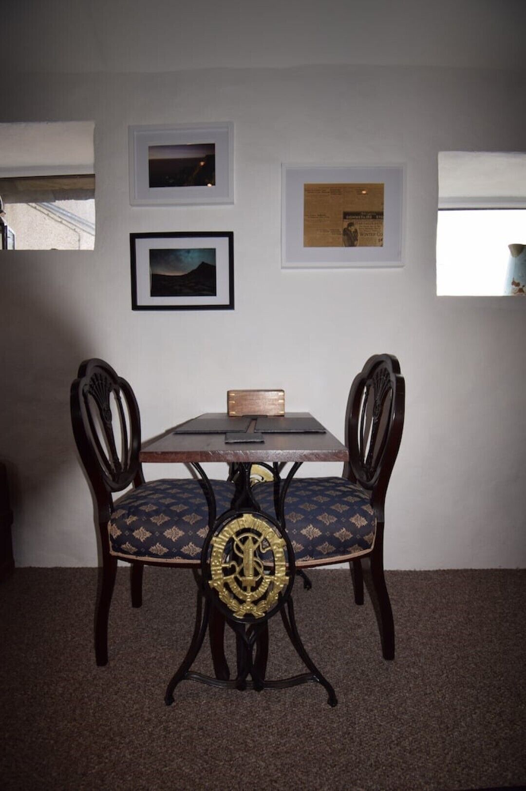 Un comedor con una mesa y dos sillas, una obra de arte enmarcada en la pared y un ventanal con vistas.