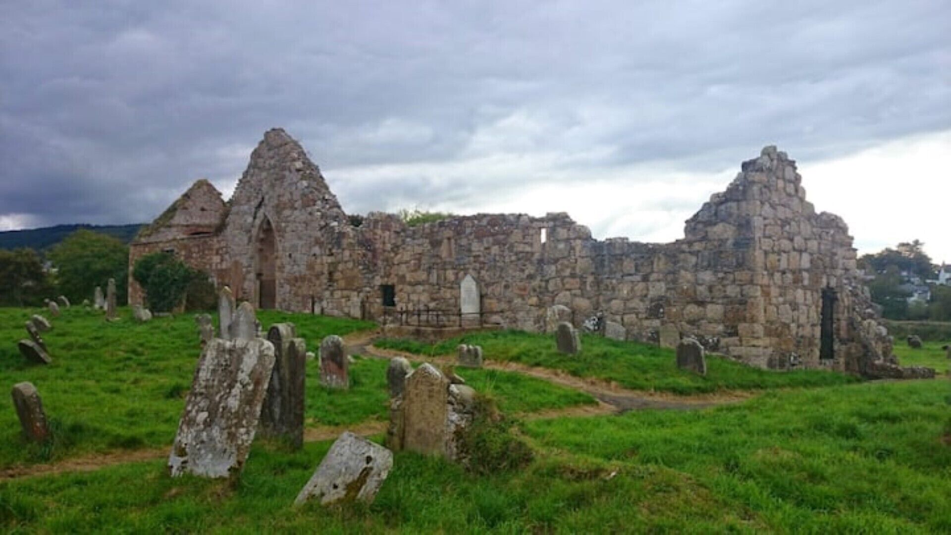 An ancient stone structure with ruins and standing stones in a grassy field.