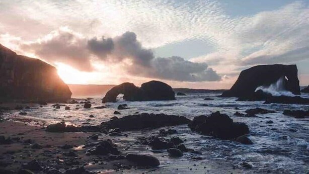 A coastal scene with large rock formations and a sunset. - Ashbrook Cottage (Ballymoney)