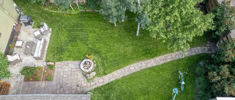 A well-maintained backyard with a stone patio, a fire pit, and a bicycle path.