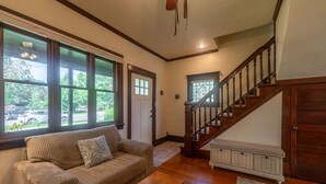 A living room with a wooden staircase, a beige sofa, and a wooden coffee table. - The Garden House in Livingston (Livingston)
