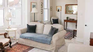 A cozy living room with a beige sofa, a small round table, a floor lamp, and a patterned rug. - 29b Lower Street (Dartmouth)