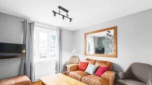 A living room with a sofa, armchairs, a wooden coffee table, a TV, and a large mirror on the wall. - Quiet Peaceful Location (Bristol)