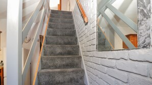 A staircase with carpeted steps and a white brick wall.