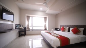 Una habitación de hotel con cama, escritorio, televisión y ventana.