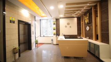 A modern reception area with a reception desk, a waiting area, a reception counter, and a window with blinds.