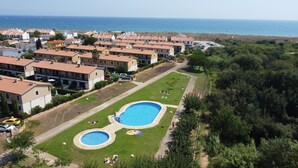 Un quartier résidentiel doté d’une piscine entourée d’une pelouse, d’une route et offrant une vue sur la mer.