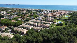 Vue aérienne d’un quartier résidentiel situé sur la côte, avec des maisons, une piscine et une plage en arrière-plan.