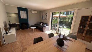 Un salon moderne comprenant un coin repas, une cuisine et une porte-fenêtre coulissante donnant sur une terrasse.