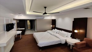 Una habitación de hotel moderna con una cama grande, un escritorio, una silla, un sofá y un ventilador de techo.