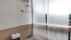 Un baño con una bañera llena de pétalos de rosa, una mesita con toallas y un calentador de pared.