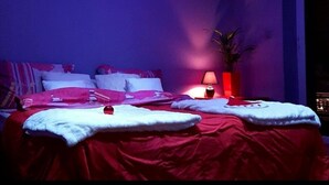 Un dormitorio con cama, almohadas, una mesita de noche con lámpara y una ventana.