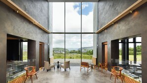 A spacious interior with large windows offering a view of a green landscape and hills. - Bracken Hide Hotel (Portree)