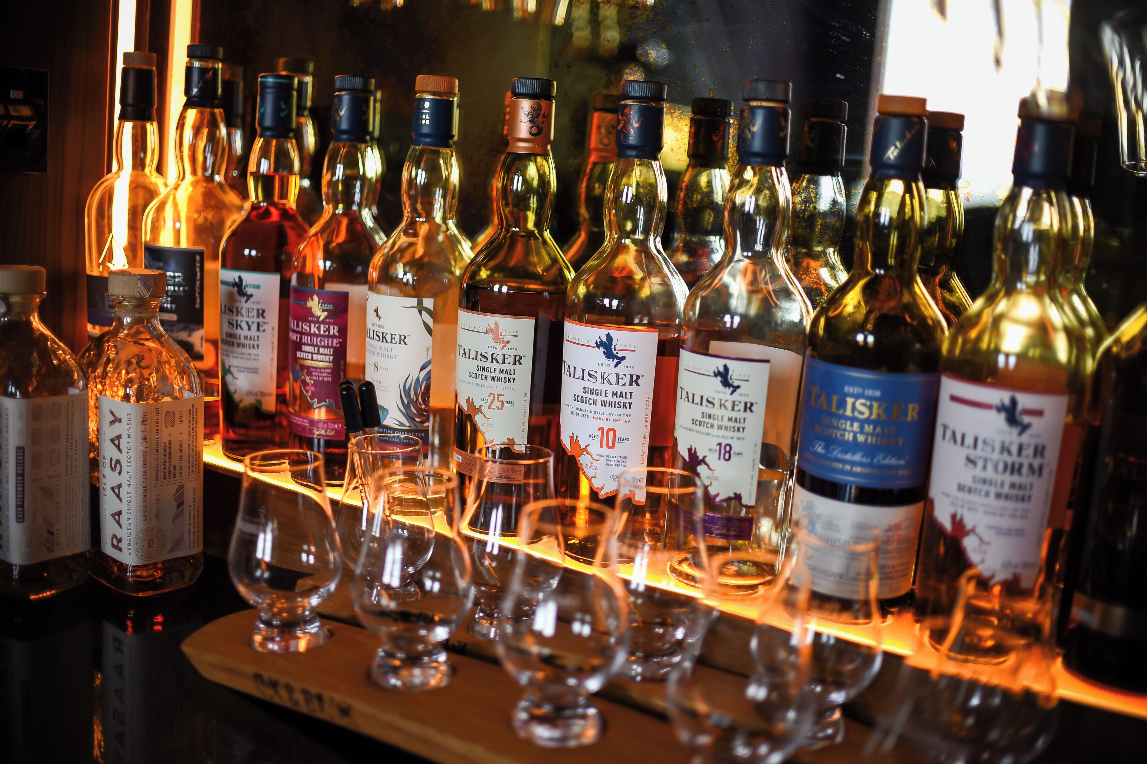 Een bar met diverse flessen whisky en glazen.