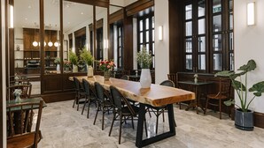 Un comedor amplio con una larga mesa de madera, varias sillas y una planta en maceta.