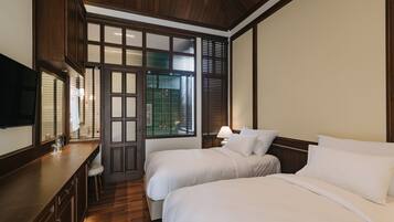 A hotel room with two beds, a wooden ceiling, a TV, and a window with blinds.