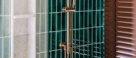 A shower with a handheld showerhead and a wall-mounted control.