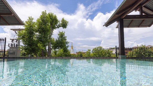 Una piscina cristalina con vistas a árboles y un edificio al fondo.