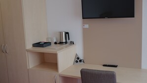 Een kamer met een bed, een bureau, een stoel, een televisie en een kledingkast.