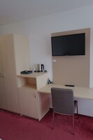Ein Zimmer mit einem Bett, einem Schreibtisch, einem Stuhl, einem Fernseher und einem Kleiderschrank.