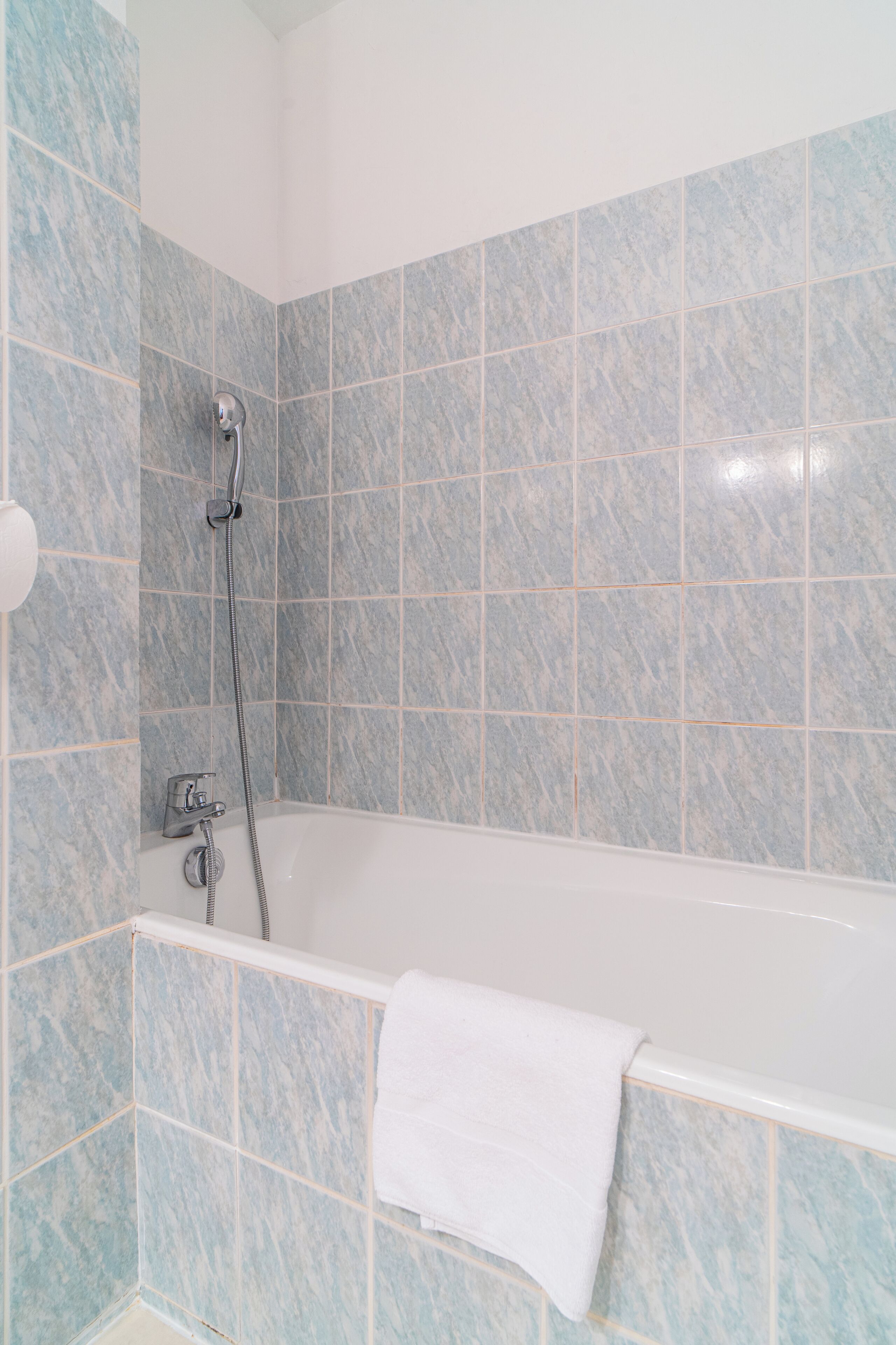 A bathroom with a bathtub, a shower, and a towel hanging on the wall.