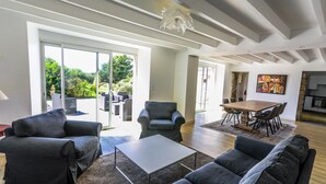 Een ruime woonkamer met een zithoek, een salontafel en een eettafel met stoelen. Er is een schuifpui die leidt naar een terras.