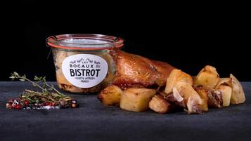 A roasted duck leg with potatoes and a jar of 'Les Bocas du Bistrot' sauce.