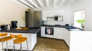 Een moderne keuken met witte kasten, roestvrijstalen apparatuur en een houten vloer.