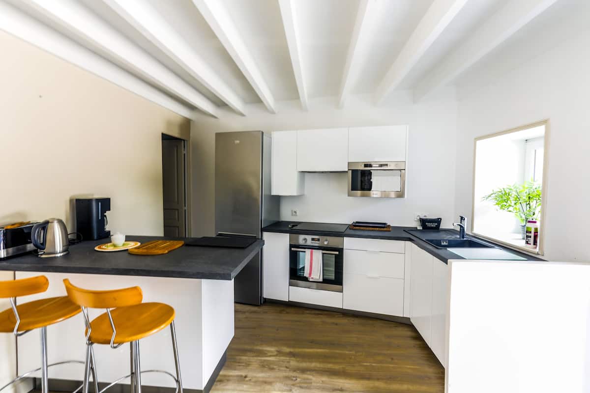 A modern kitchen with white cabinets, stainless steel appliances, and a wooden floor.