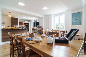A dining area with a wooden table, chairs, and a coffee station. - La Villa Bel Air (Flamanville)