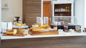 Een ontbijtbuffet met brood, gebak en toevoegingen.