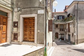 A narrow street with cobblestone pavement, a wooden door with a sign reading "VIA POGGIO", and a building with a balcony. - House Court - Irpinia (Montemarano)