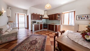 A spacious living area with a sofa, a dining table, and a kitchen with wooden cabinets and a tiled backsplash. - House Court - Irpinia (Montemarano)