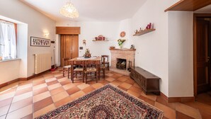 A cozy living room with a fireplace, a dining table, and a patterned rug. - House Court - Irpinia (Montemarano)