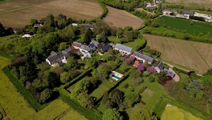 Vista aerea di una zona residenziale con case, campi verdi e una piscina.